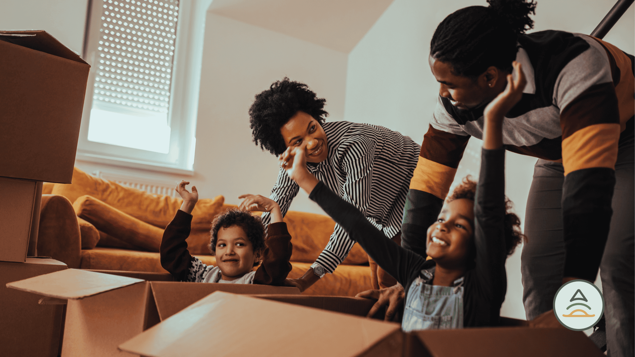 Man and woman with two children cheering and smiling in a living room with moving boxes.